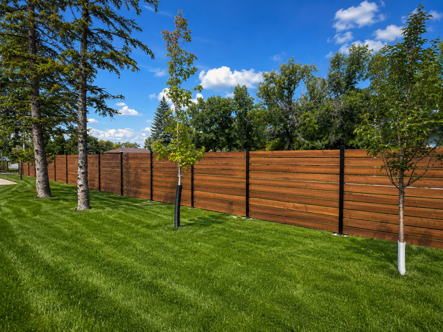 Hybrid fence with steel structural posts and horizontal wood infill around a landscaped backyard